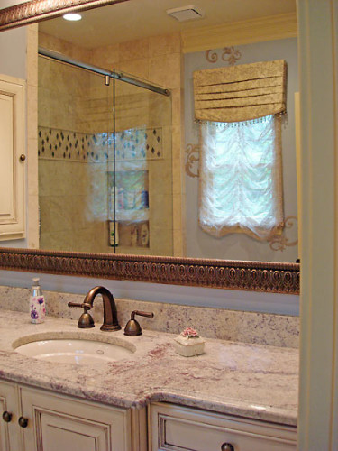 Feminine bathroom remodel with rose-toned granite, cream cabinets, stone tile with glass accents and stenciled walls.