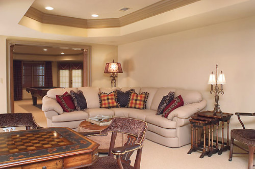 A comfortable curved couch in the basement game room with custom pillows